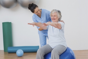 Instructor assisting senior woman during physical therapy